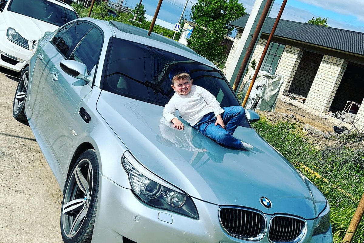 Hasbulla posing on the hood of a silver BMW.