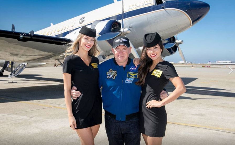 Mark Kelly posing with Breitling models dressed as flight attendants 