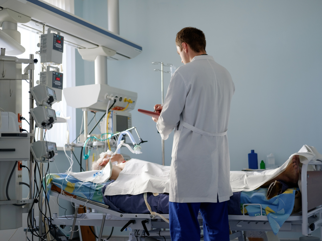 doctor standing over a comatose patient